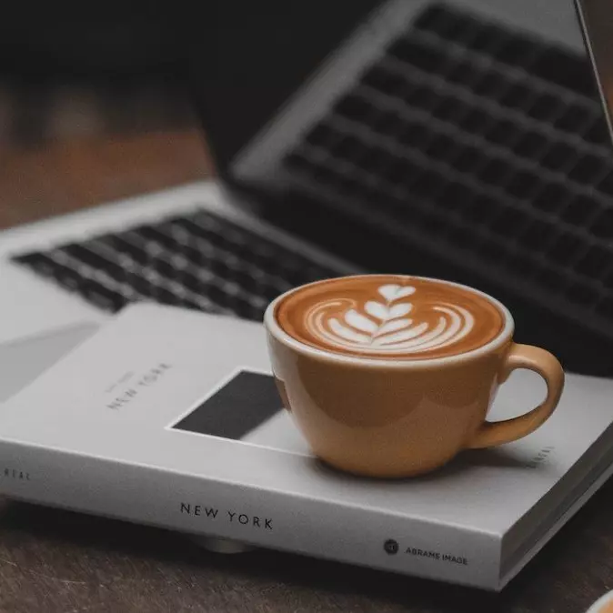 Picture of a coffee cup by a laptop.